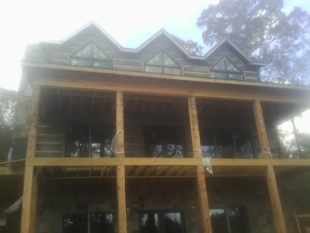 Dormers and porch framing on a large log home under construction — Roof Coating work by our crew in Bowersville